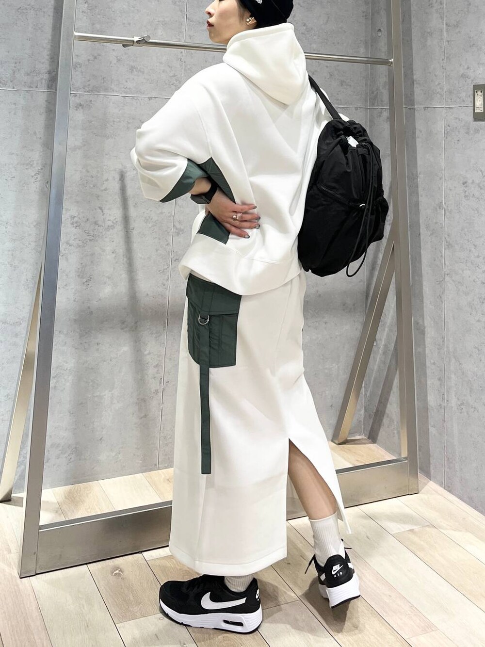 ブラック系のショルダーバッグ、ホワイト系のスカート、ホワイト系のパーカーを着用したレディースの冬コーディネートの1枚目の写真