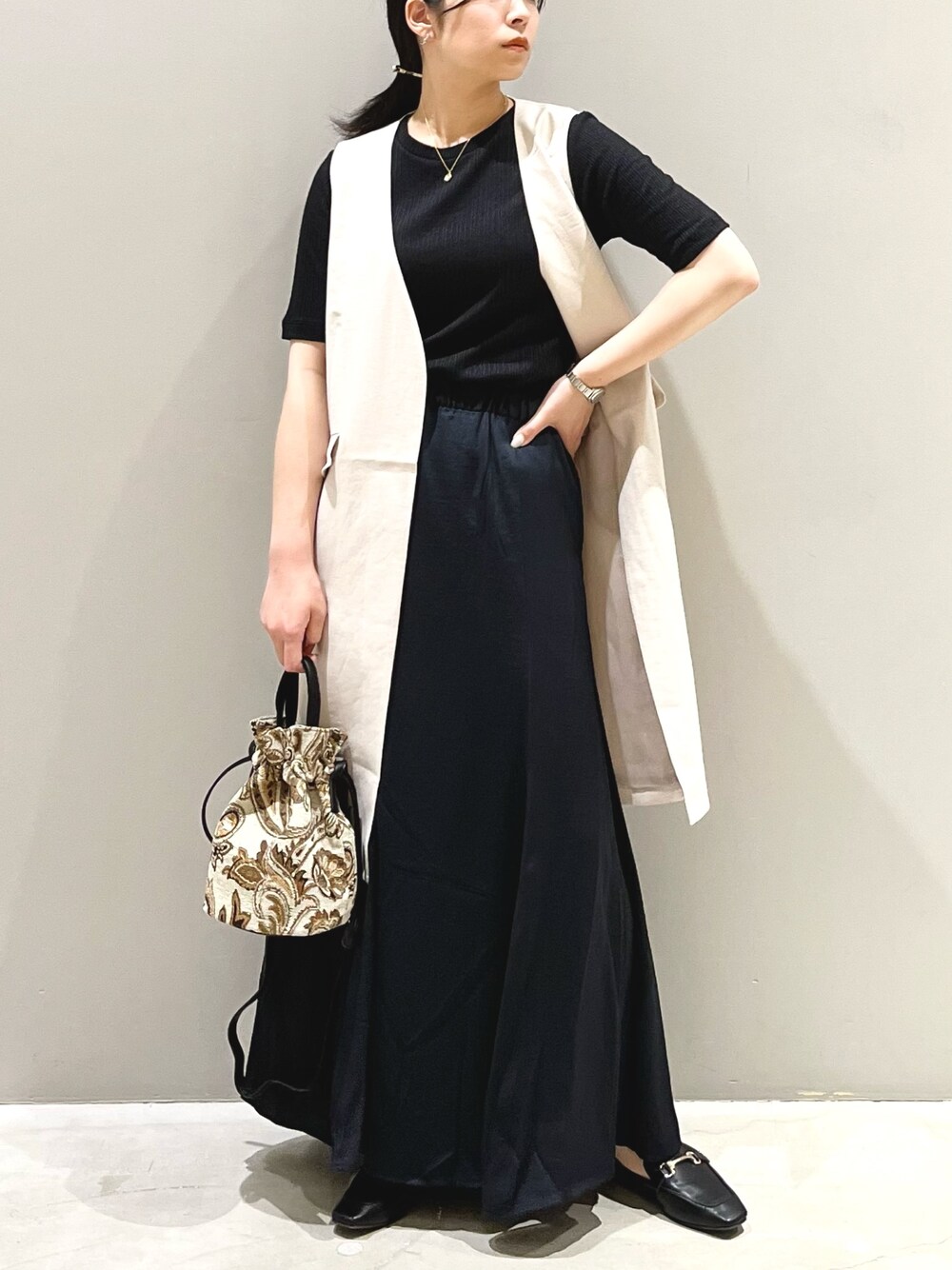 ブラウン系のショルダーバッグ、ブラック系のローファー、ブラック系のスカートを着用したレディースの夏コーディネートの2枚目の写真