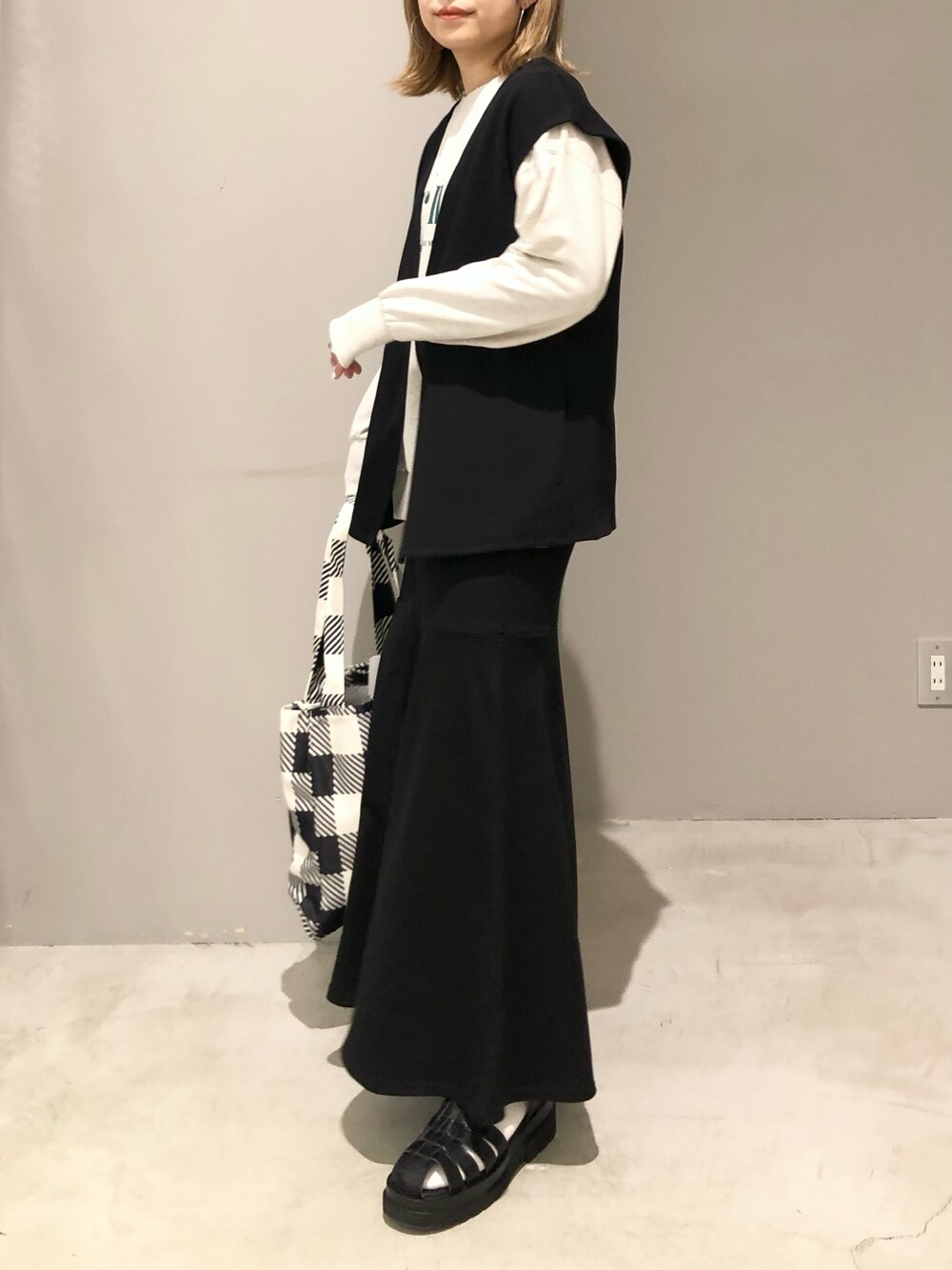 ブラック系のスカート、ブラック系のショルダーバッグ、ブラック系のサンダルを着用したレディースの春コーディネートの2枚目の写真