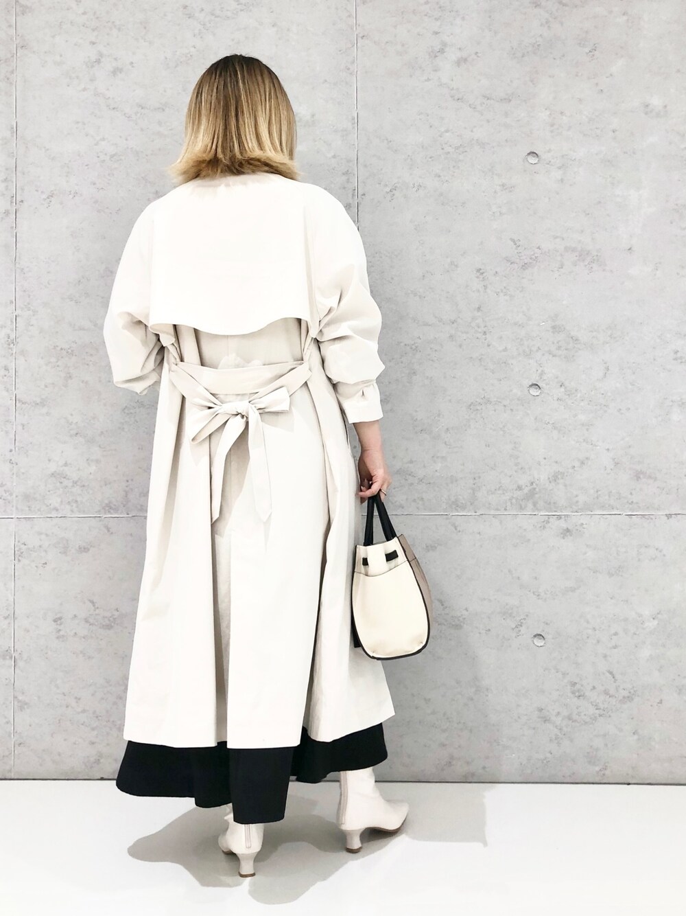 ブラウン系のショルダーバッグ、ホワイト系のジャケット/アウター、ブラック系のスカートを着用したレディースの冬コーディネートの2枚目の写真