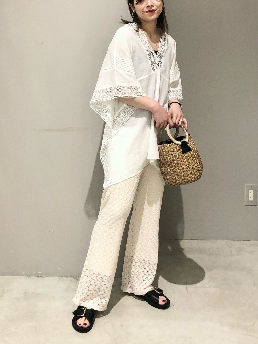 ブラック系のかごバッグ、ホワイト系のその他パンツ、ブラック系のサンダルを着用したレディースの春コーディネートの2枚目の写真