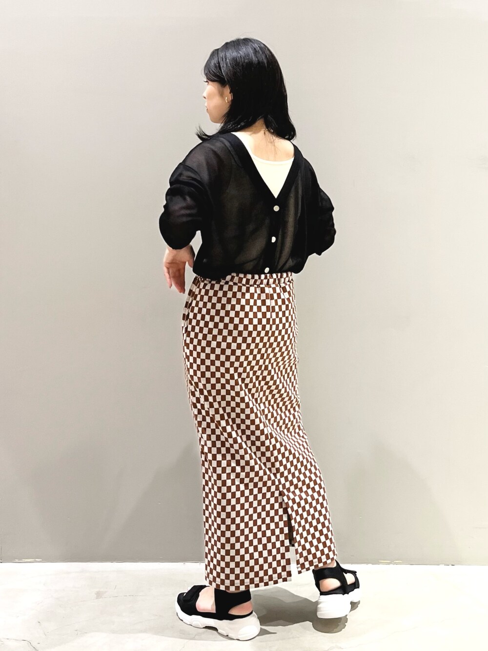 ブラック系のサンダル、ブラック系のニット/セーター、ゴールド系のイヤリングを着用したレディースの夏コーディネートの2枚目の写真