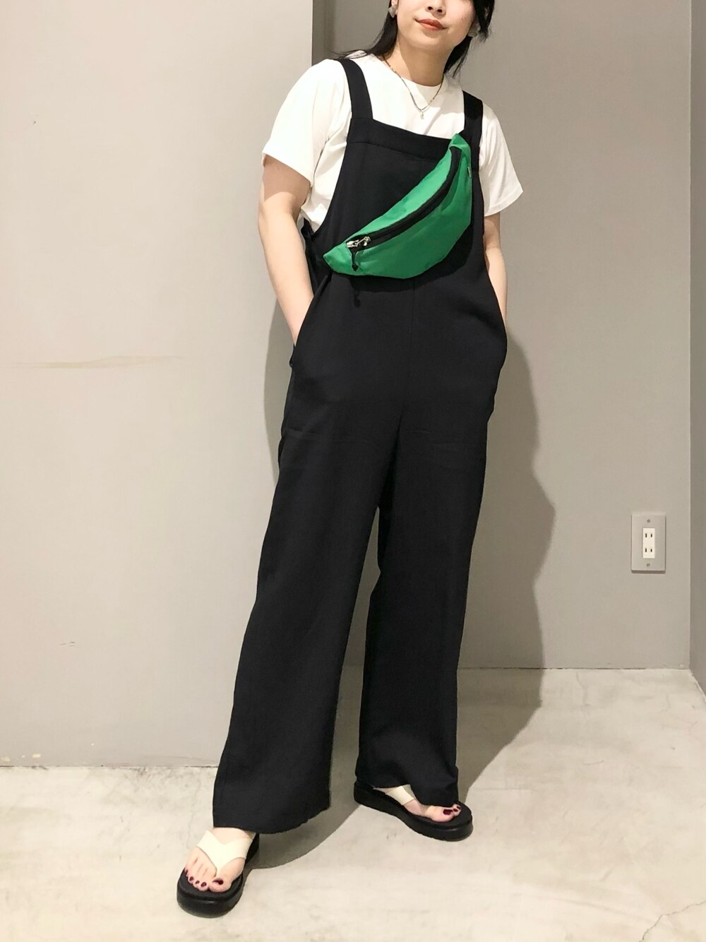 ブラック系のサロペット/オーバーオール、ホワイト系のサンダル、ホワイト系のTシャツ/カットソーを着用したレディースの夏コーディネートの3枚目の写真