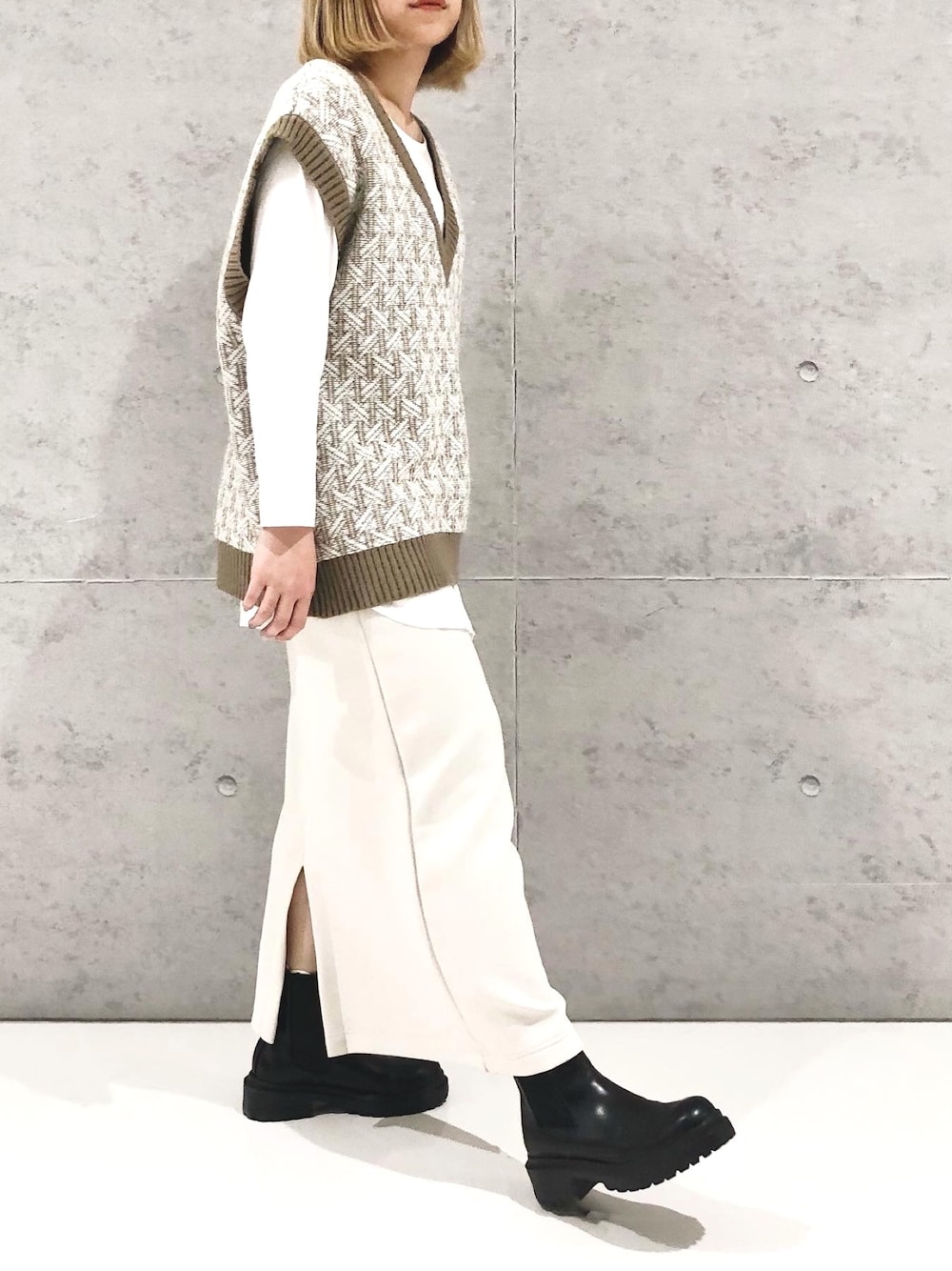 ベージュ系のスカート、ブラック系のブーツ、ホワイト系のTシャツ/カットソーを着用したレディースの冬コーディネートの5枚目の写真