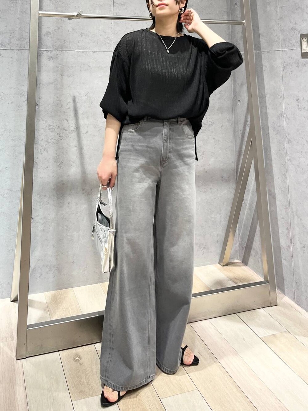 シルバー系のハンドバッグ、ブラック系のサンダル、グレー系のデニムパンツを着用したレディースの春コーディネートの1枚目の写真