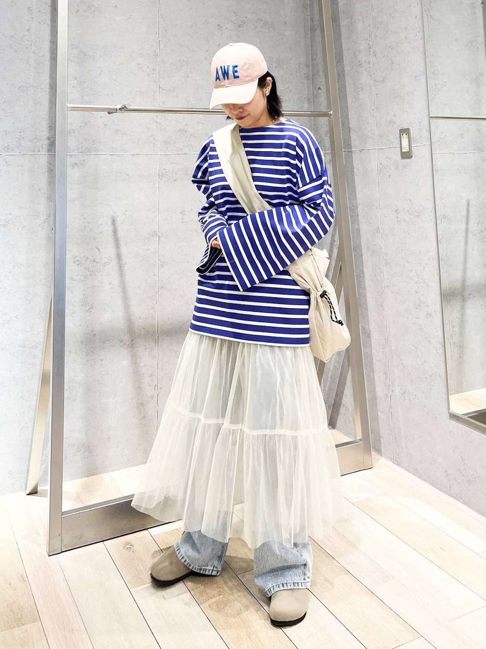 ホワイト系のスカート、パープル系のTシャツ/カットソー、ブルー系のデニムパンツを着用したレディースの冬コーディネートの1枚目の写真