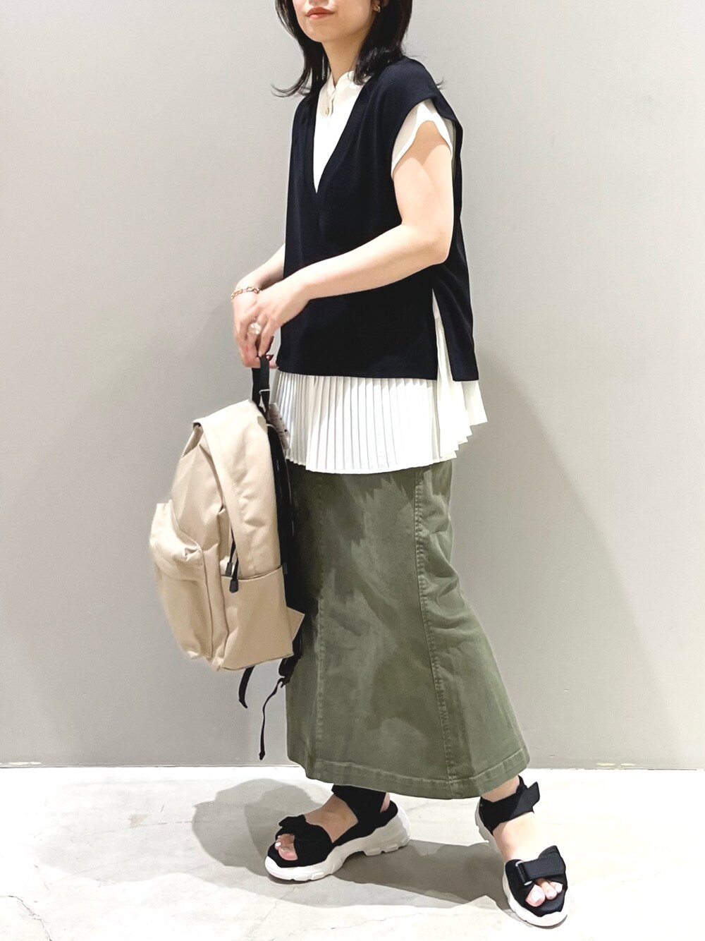 ブラック系のベスト、ホワイト系のシャツ/ブラウス、グリーン系のスカートを着用したレディースの夏コーディネートの5枚目の写真