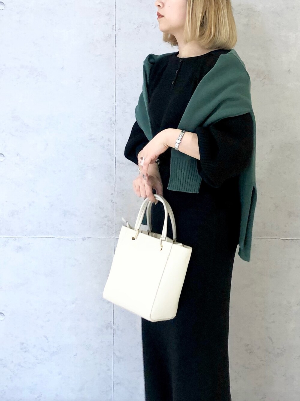 ブラック系のスカート、ホワイト系のハンドバッグ、その他のブーツを着用したレディースの冬コーディネートの3枚目の写真