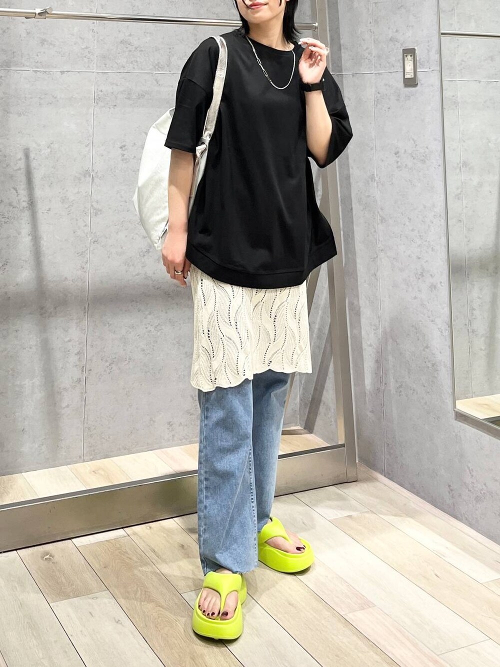 イエロー系のサンダル、グレー系のショルダーバッグ、ブルー系のデニムパンツを着用したレディースの春コーディネートの1枚目の写真