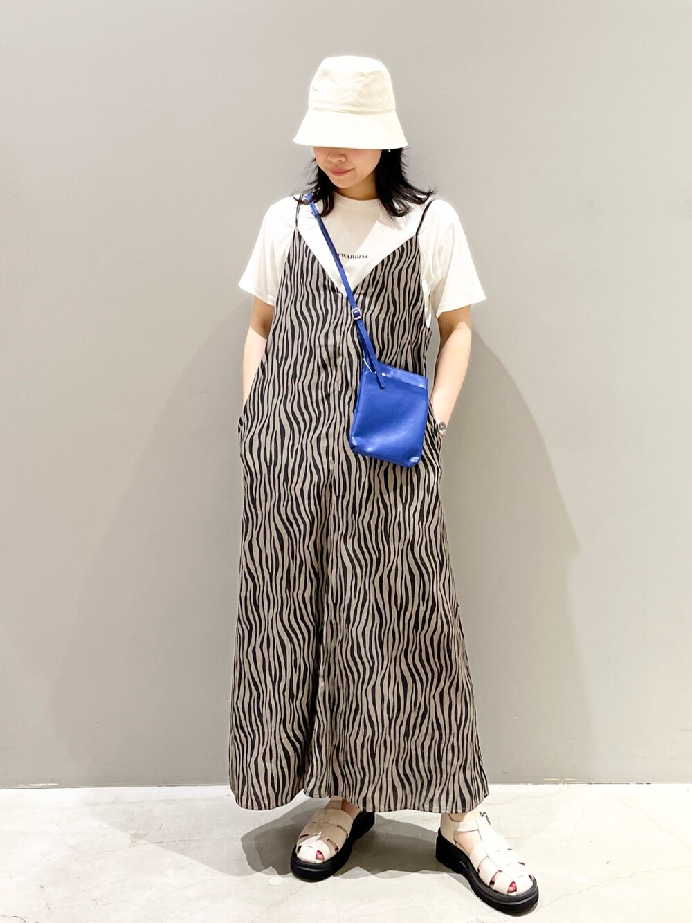 ブラウン系のワンピース、ブルー系のバッグ、ホワイト系のTシャツ/カットソーを着用したレディースの夏コーディネートの2枚目の写真