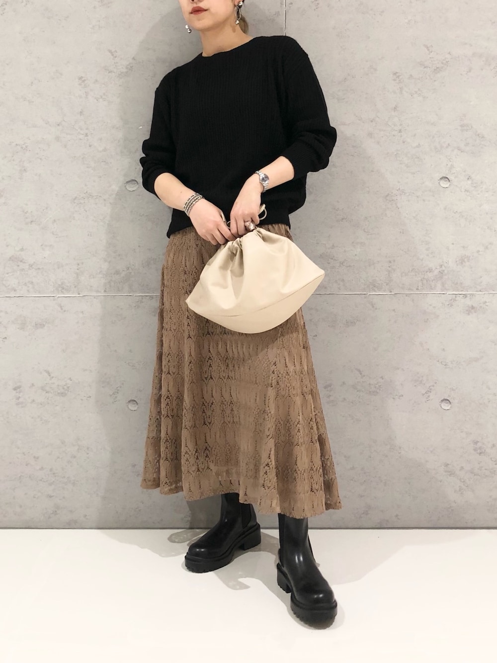 ブラック系のニット/セーター、ブラウン系のスカート、ブラック系のブーツを着用したレディースの冬コーディネートの1枚目の写真