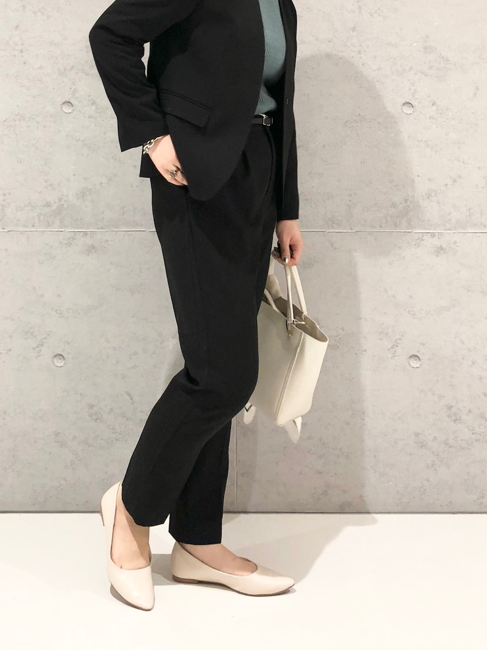 ホワイト系のハンドバッグ、ホワイト系のパンプス、ブラック系のスラックスを着用したレディースの冬コーディネートの3枚目の写真