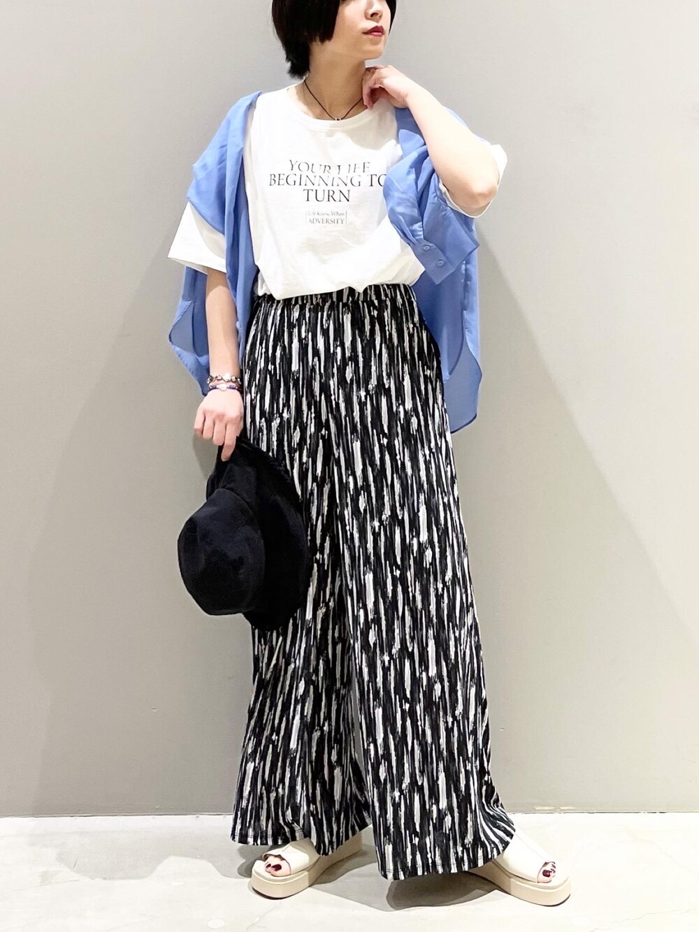 ブラック系のその他パンツ、ベージュ系のサンダル、ホワイト系のTシャツ/カットソーを着用したレディースの春コーディネートの1枚目の写真