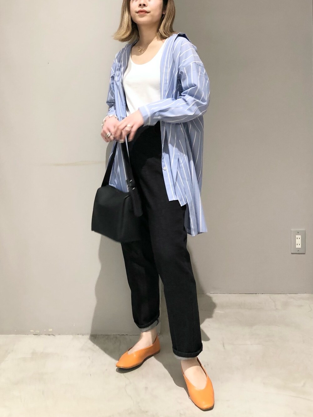 オレンジ系のパンプス、ブラック系のデニムパンツ、ブラック系のショルダーバッグを着用したレディースの春コーディネートの2枚目の写真