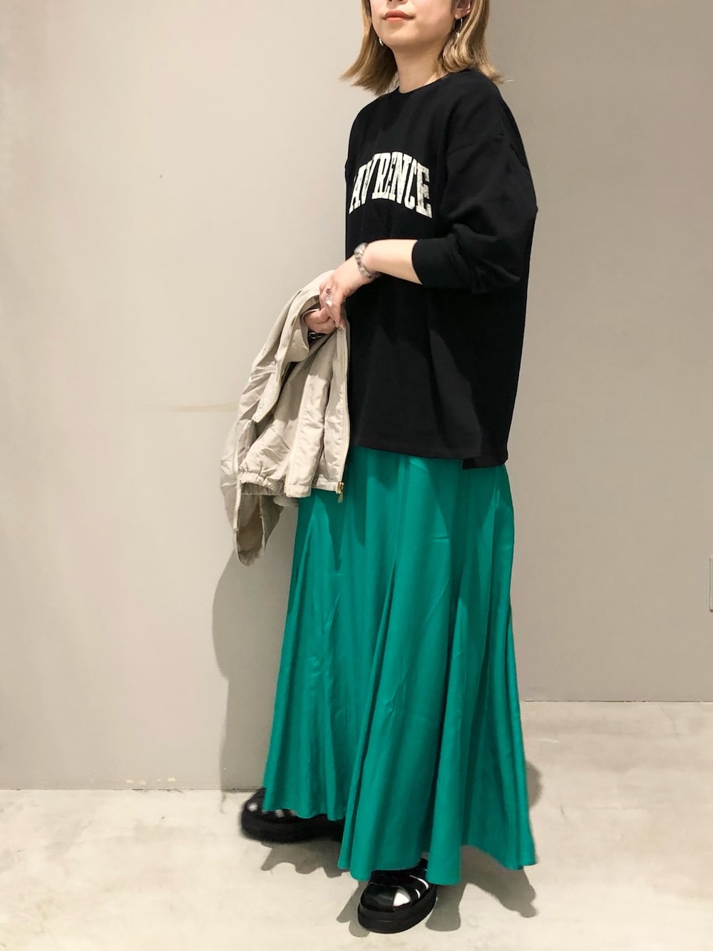 グリーン系のスカート、ブラック系のTシャツ/カットソー、ブラック系のサンダルを着用したレディースの春コーディネートの3枚目の写真