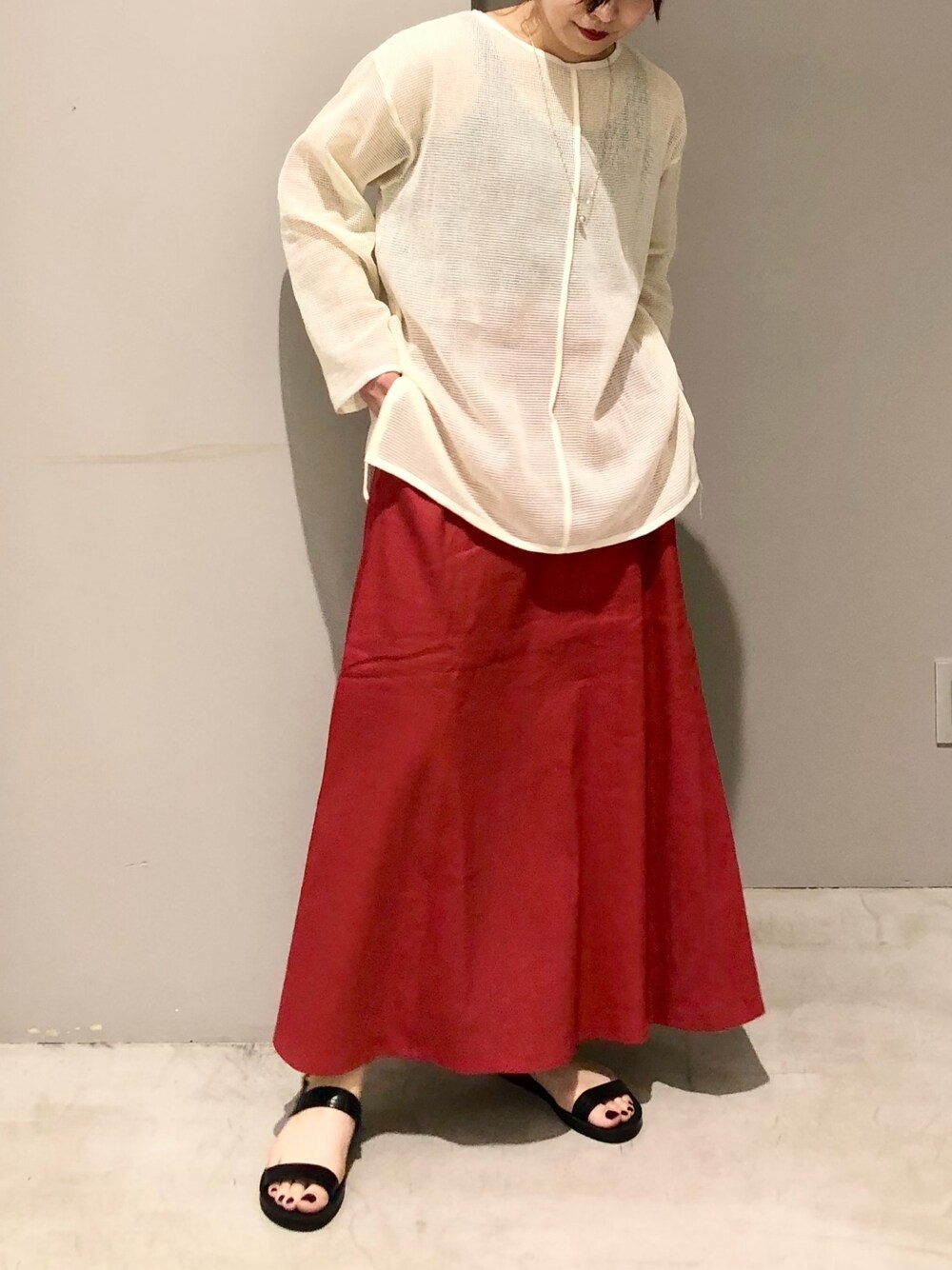 レッド系のスカート、ブラック系のサンダル、ホワイト系のニット/セーターを着用したレディースの夏コーディネートの2枚目の写真