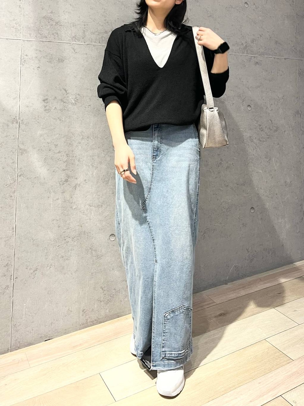 グレー系のTシャツ/カットソー、ブルー系のデニムスカート、ブラック系のニット/セーターを着用したレディースの冬コーディネートの1枚目の写真