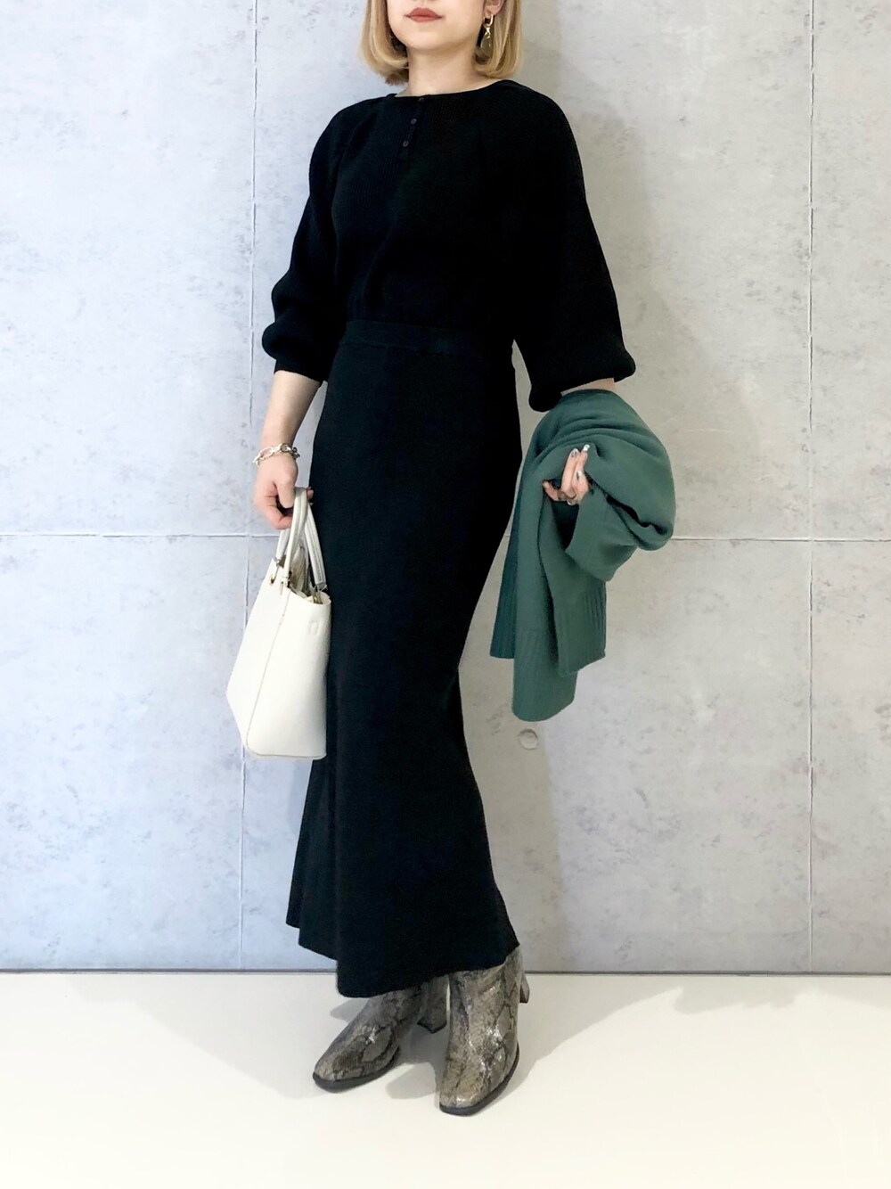 ブラック系のスカート、ホワイト系のハンドバッグ、その他のブーツを着用したレディースの冬コーディネートの2枚目の写真