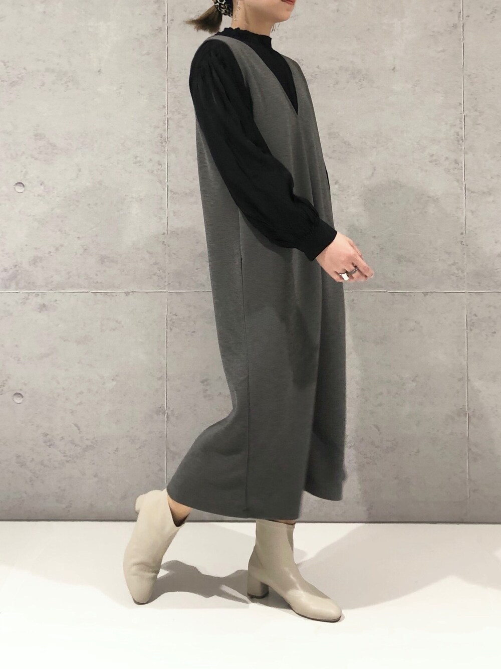 グレー系のジャンパースカート、ホワイト系のブーツ、ブラック系のシャツ/ブラウスを着用したレディースの秋コーディネートの1枚目の写真
