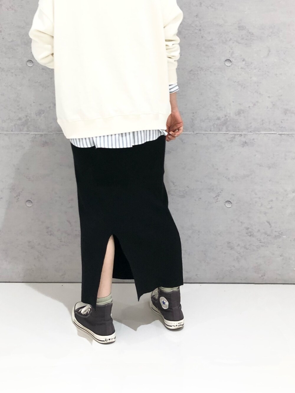 ブラック系のスカート、グレー系のスニーカー、ホワイト系のスウェットを着用したレディースの冬コーディネートの2枚目の写真