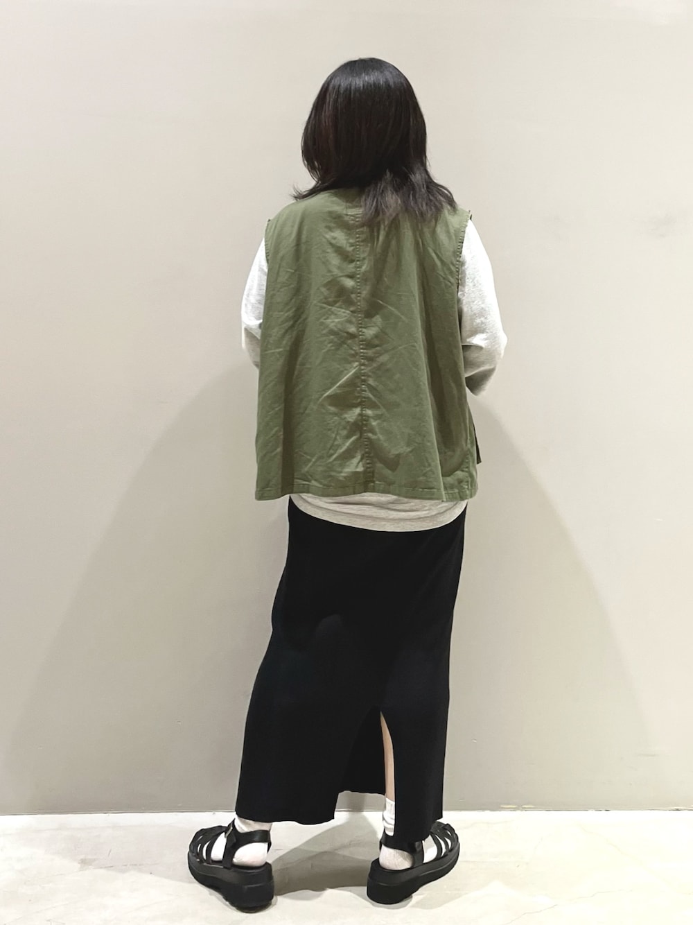 グリーン系のジャケット/アウター、ブラック系のスカート、ブラック系のサンダルを着用したレディースの秋コーディネートの3枚目の写真