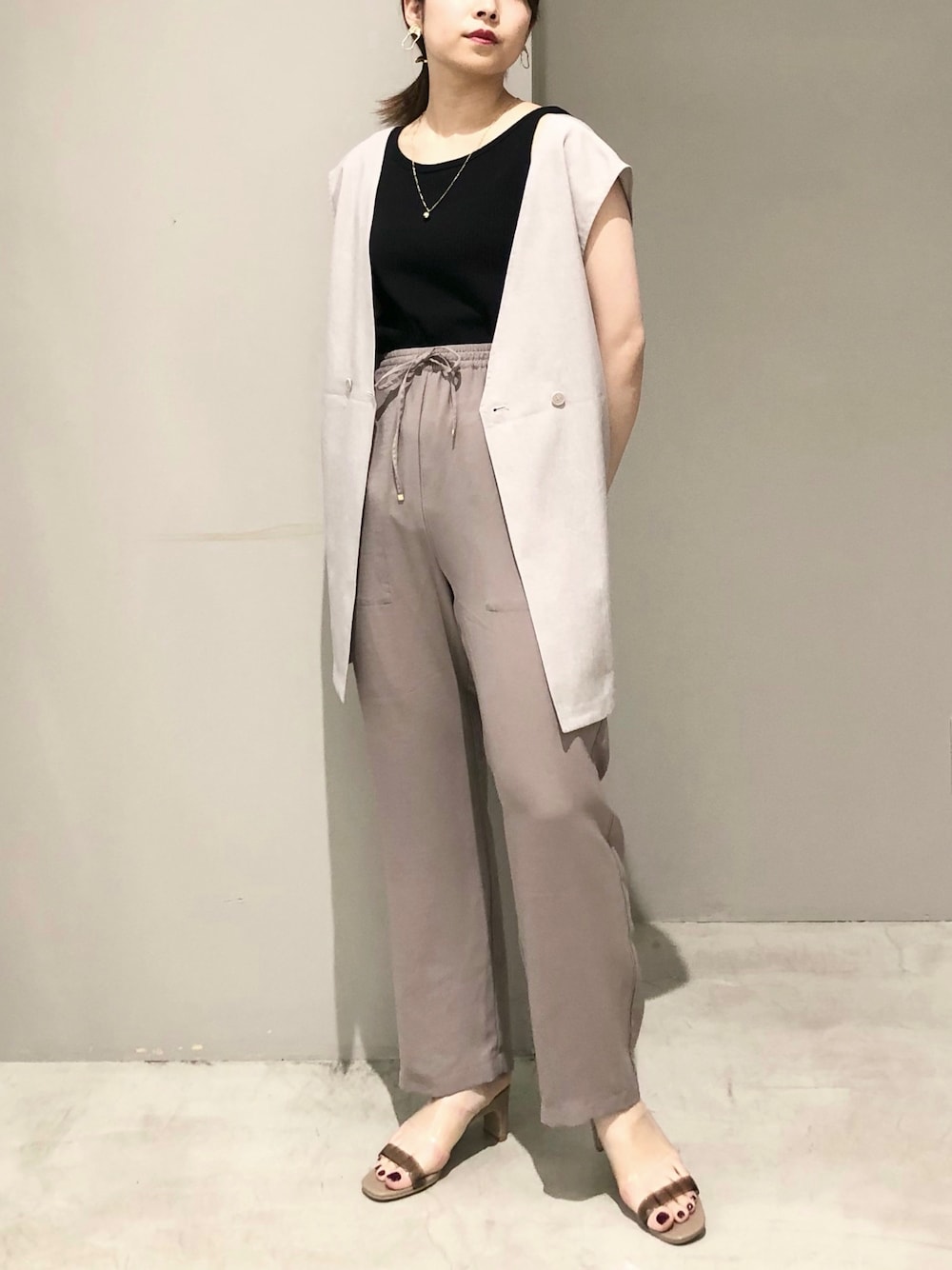 ブラック系のかごバッグ、ベージュ系のサンダル、ブラウン系のその他パンツを着用したレディースの夏コーディネートの2枚目の写真