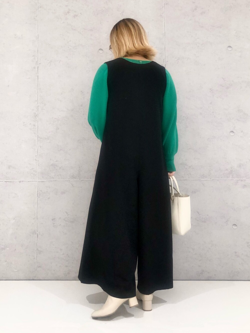 グリーン系のニット/セーター、ホワイト系のハンドバッグ、ホワイト系のブーツを着用したレディースの冬コーディネートの3枚目の写真