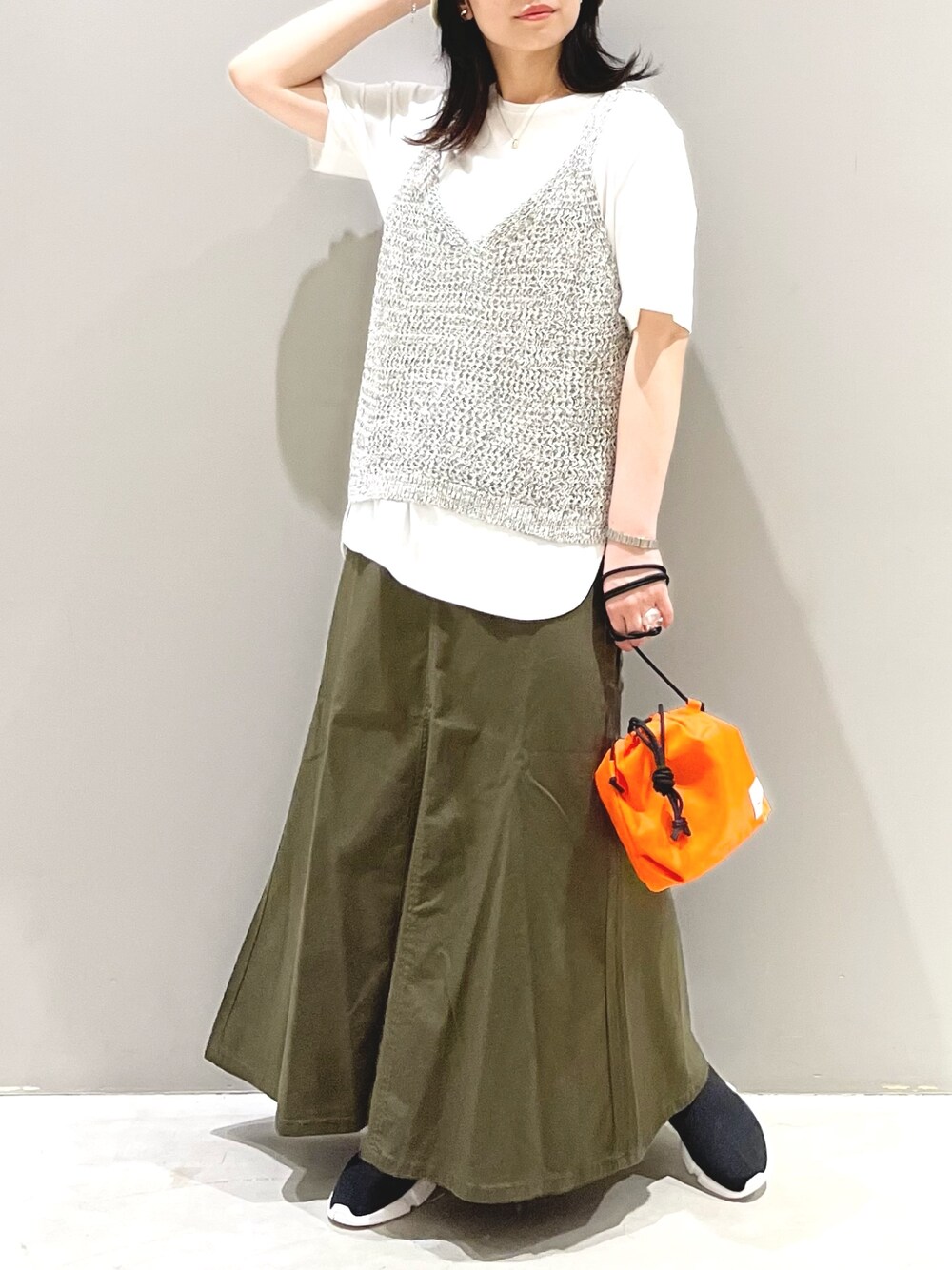 グリーン系のスカート、ブラック系のシューズ、オレンジ系のショルダーバッグを着用したレディースの秋コーディネートの2枚目の写真