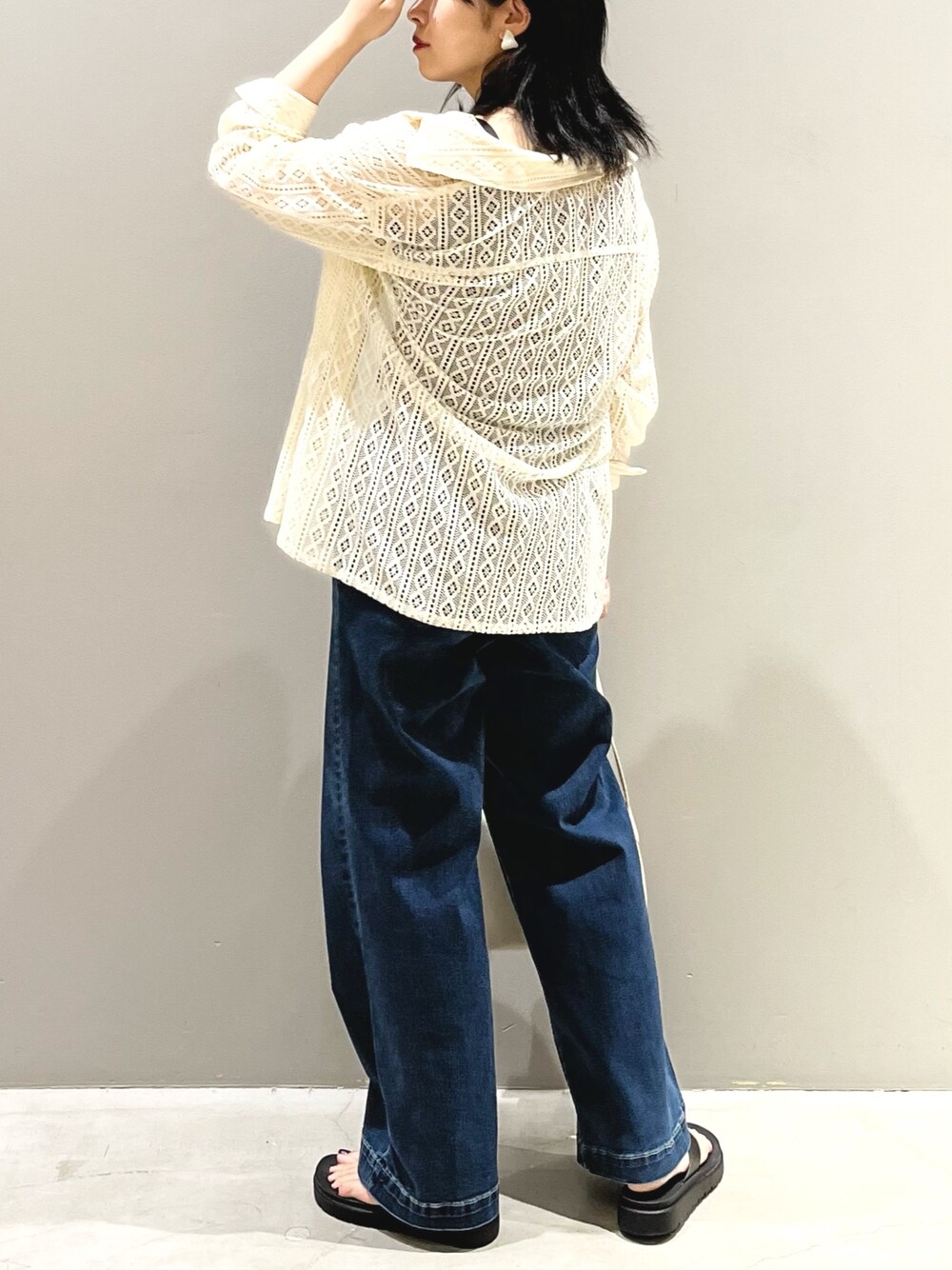 ブルー系のデニムパンツ、ホワイト系のショルダーバッグ、ブラック系のサンダルを着用したレディースの夏コーディネートの3枚目の写真