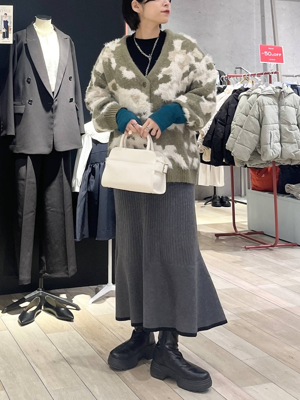 ブラック系のニット/セーター、ブラック系のスカート、ブラック系のブーツを着用したレディースの冬コーディネートの1枚目の写真