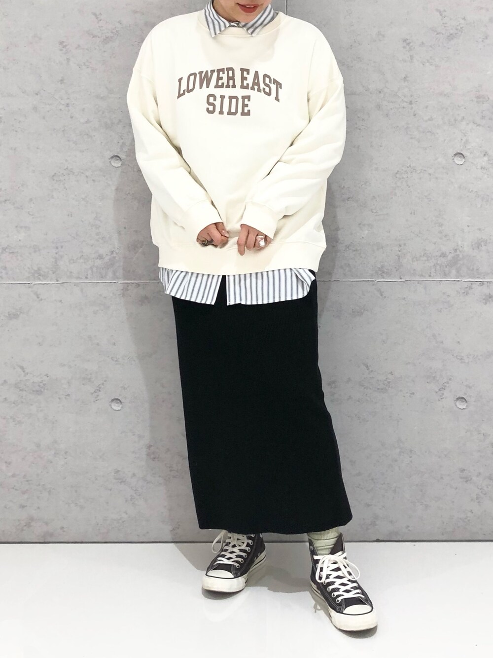 ブラック系のスカート、グレー系のスニーカー、ホワイト系のスウェットを着用したレディースの冬コーディネートの3枚目の写真