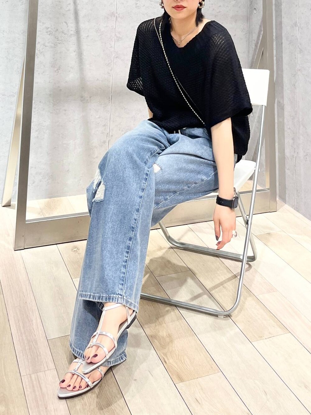 シルバー系のサンダル、ブラック系のニット/セーター、ブルー系のデニムパンツを着用したレディースの春コーディネートの1枚目の写真