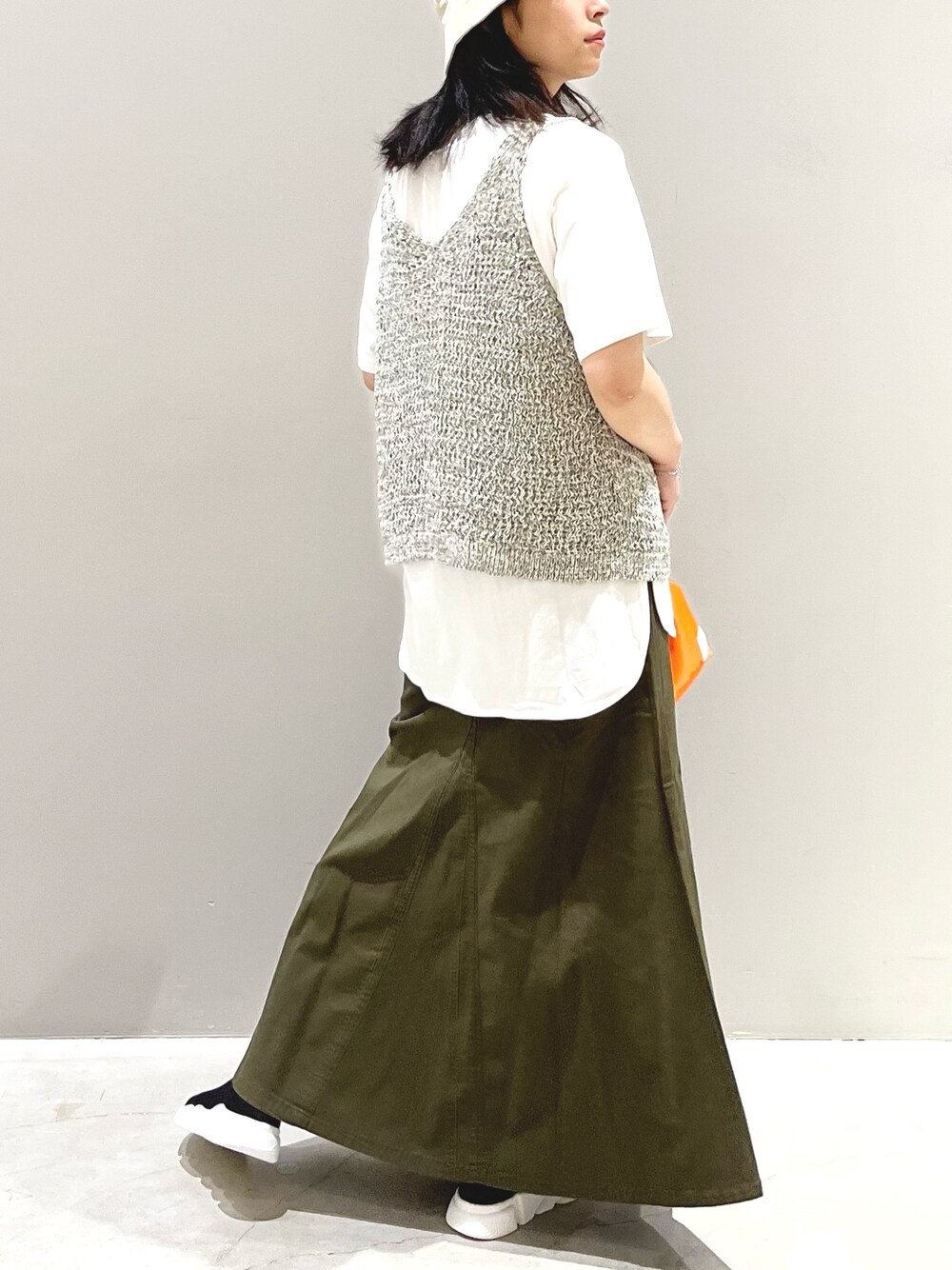 グリーン系のスカート、ブラック系のシューズ、オレンジ系のショルダーバッグを着用したレディースの秋コーディネートの3枚目の写真