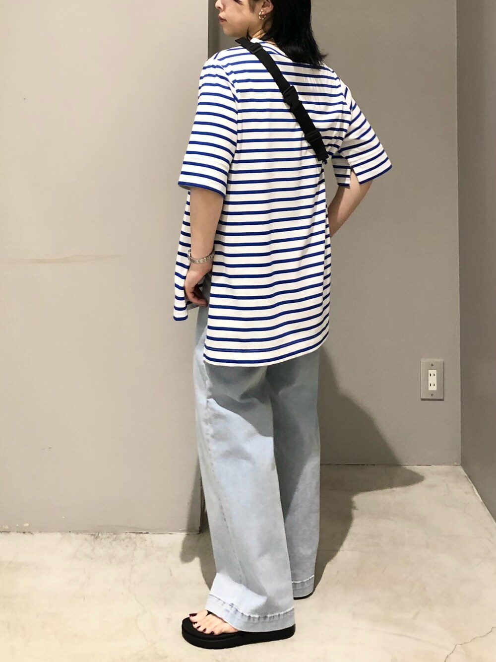 ブルー系のデニムパンツ、ブラック系のサンダル、ブルー系のTシャツ/カットソーを着用したレディースの夏コーディネートの3枚目の写真