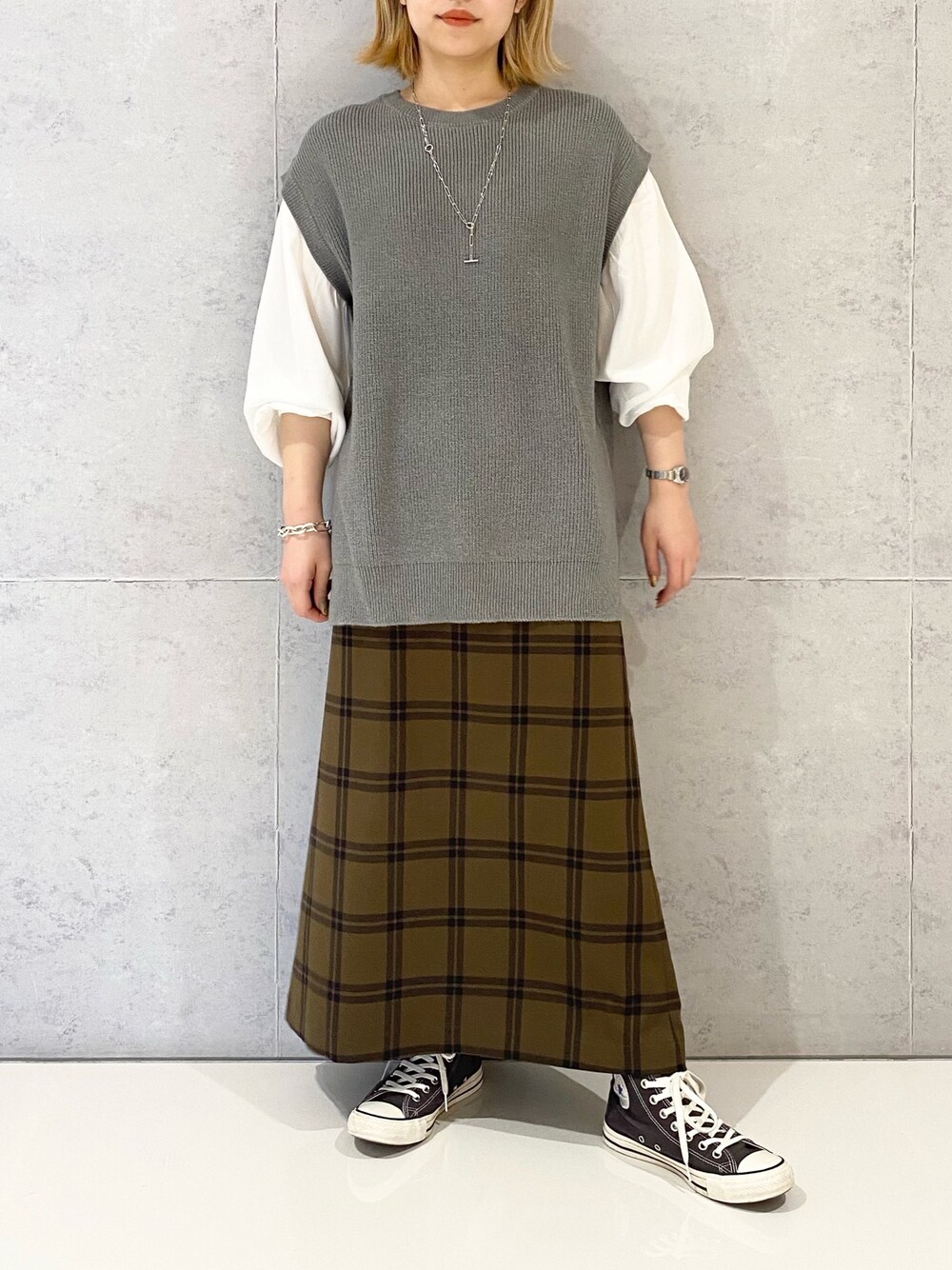 グレー系のニット/セーター、ブラウン系のスカート、グレー系のスニーカーを着用したレディースの冬コーディネートの3枚目の写真