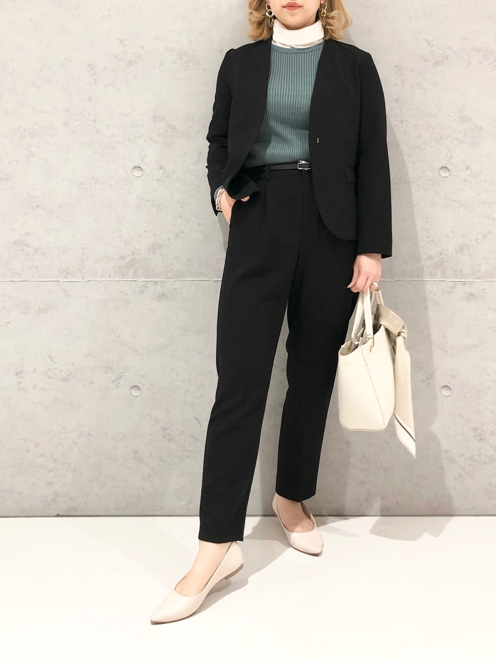 ホワイト系のハンドバッグ、ホワイト系のパンプス、ブラック系のスラックスを着用したレディースの冬コーディネートの2枚目の写真