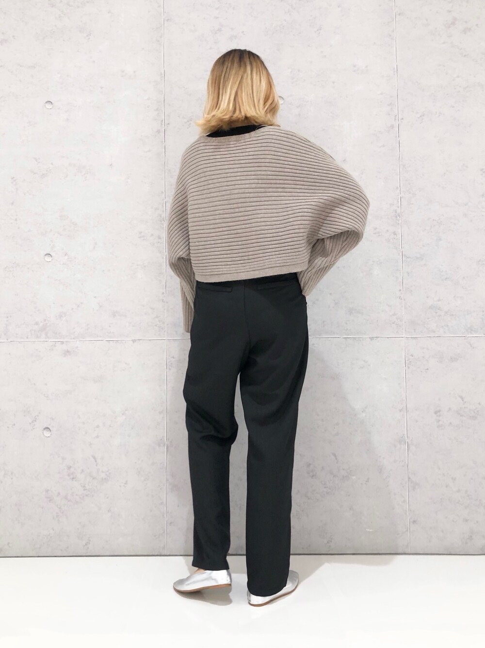 ブラック系のスラックス、シルバー系のパンプス、ベージュ系のニット/セーターを着用したレディースの冬コーディネートの3枚目の写真