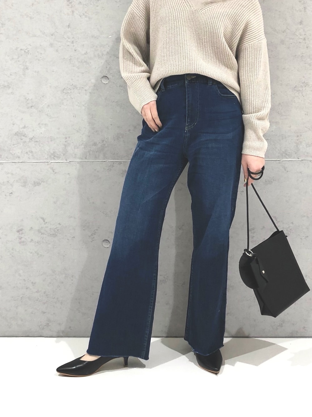 ブルー系のデニムパンツ、ブラック系のパンプス、ブラック系のショルダーバッグを着用したレディースの冬コーディネートの4枚目の写真