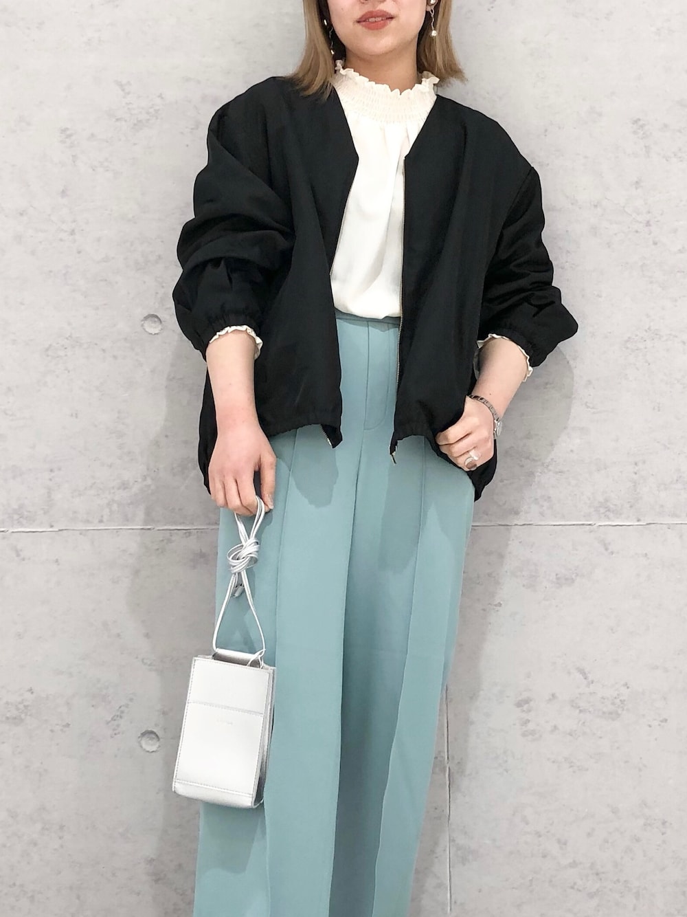 シルバー系のパンプス、グリーン系のスラックス、シルバー系のショルダーバッグを着用したレディースの春コーディネートの3枚目の写真