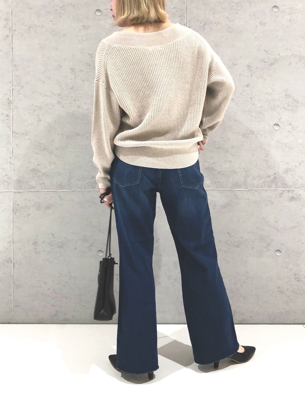 ブルー系のデニムパンツ、ブラック系のパンプス、ブラック系のショルダーバッグを着用したレディースの冬コーディネートの2枚目の写真