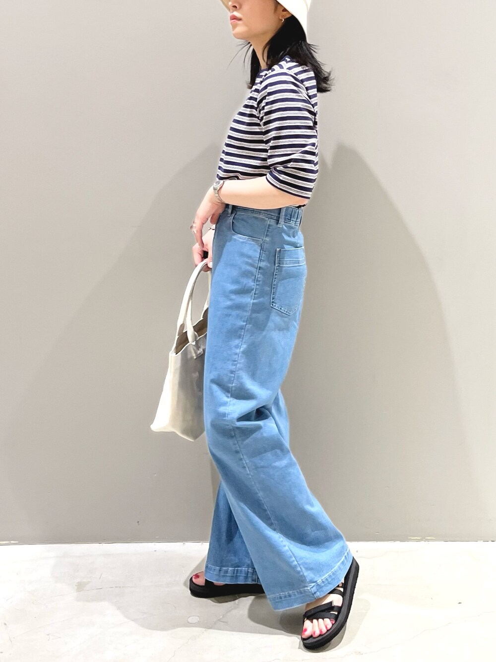 ブルー系のTシャツ/カットソー、ブルー系のデニムパンツ、ホワイト系のトートバッグを着用したレディースの夏コーディネートの3枚目の写真