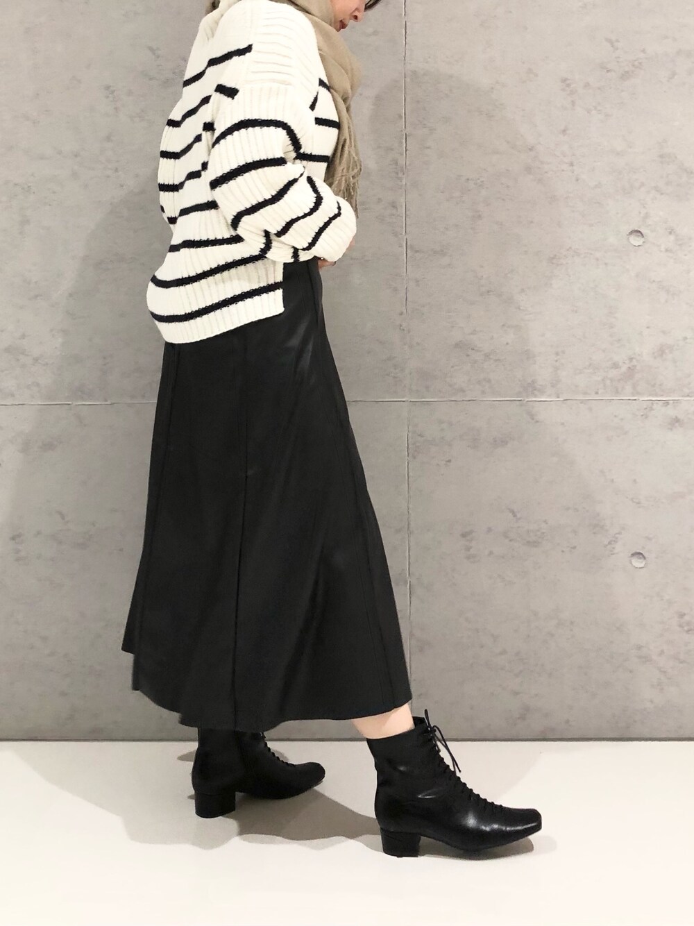 ホワイト系のニット/セーター、ブラック系のスカート、ブラック系のブーツを着用したレディースの冬コーディネートの3枚目の写真