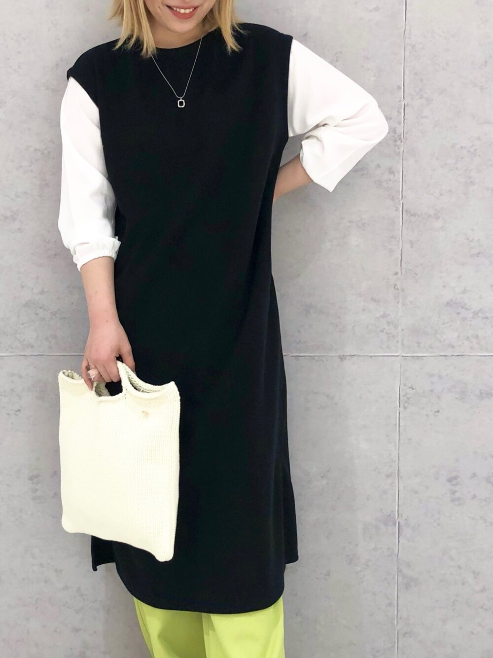 ブラック系のワンピース/ドレス、イエロー系のスラックス、ホワイト系のパンプスを着用したレディースの冬コーディネートの2枚目の写真