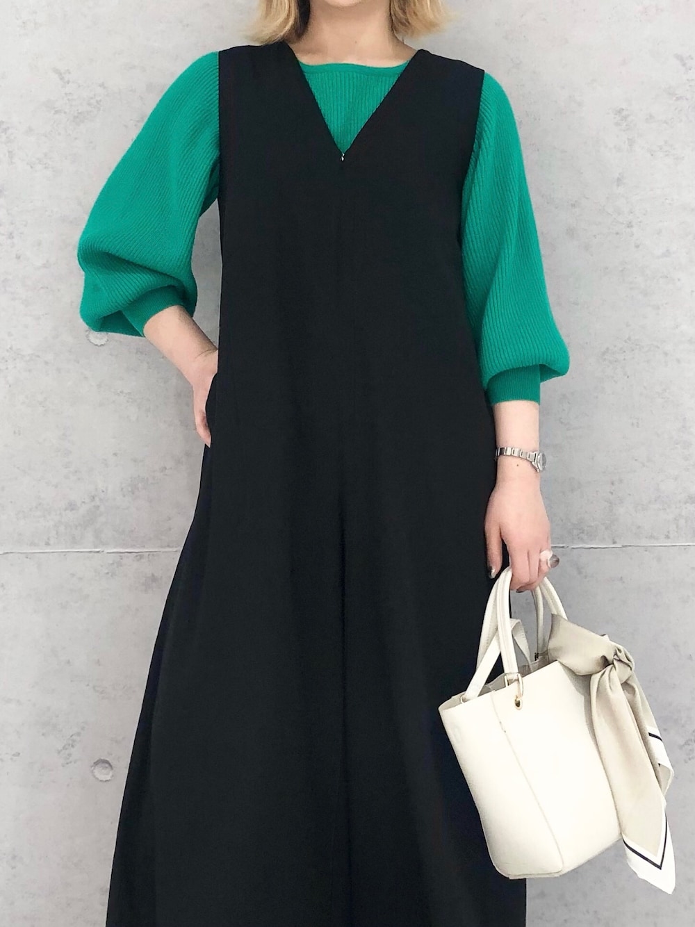 グリーン系のニット/セーター、ホワイト系のハンドバッグ、ホワイト系のブーツを着用したレディースの冬コーディネートの2枚目の写真