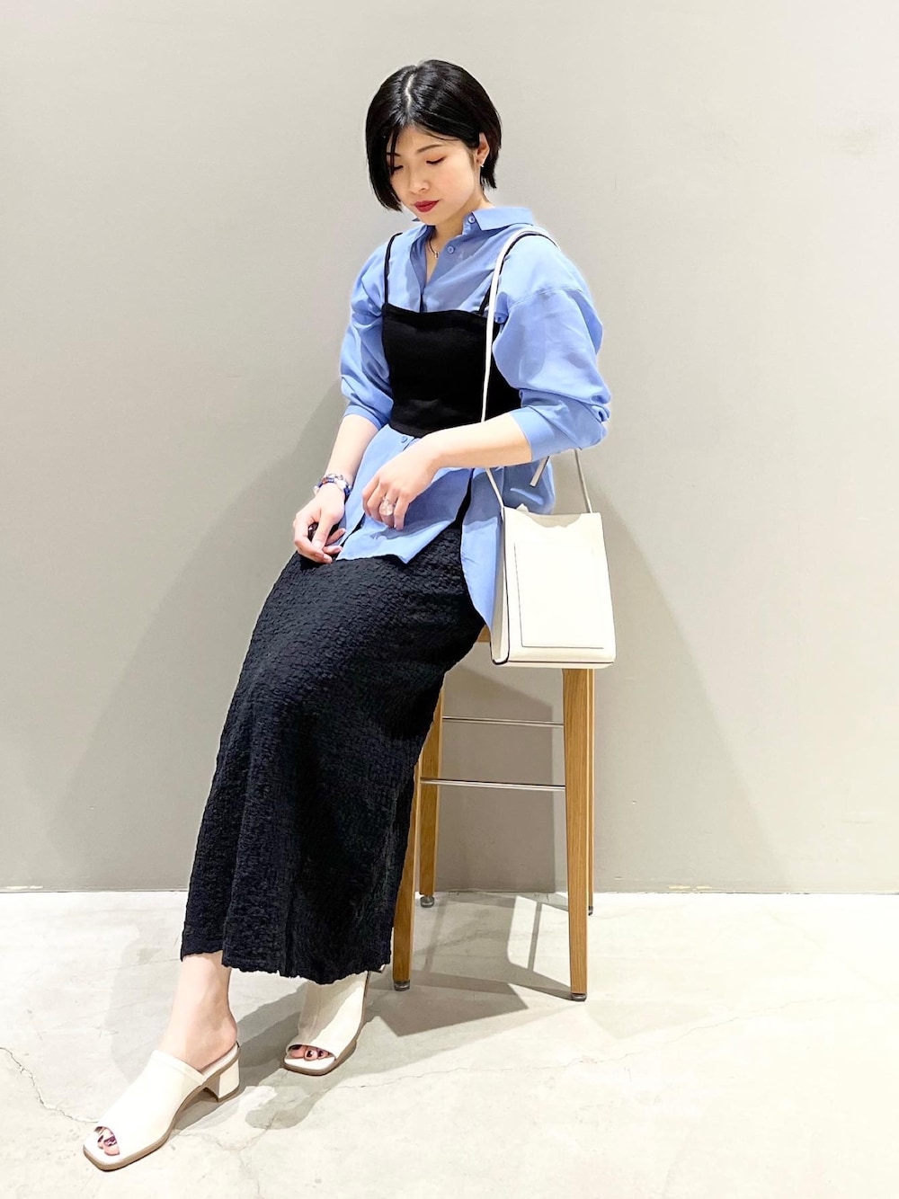 ホワイト系のサンダル、ブラック系のスカート、ブルー系のシャツ/ブラウスを着用したレディースの春コーディネートの1枚目の写真