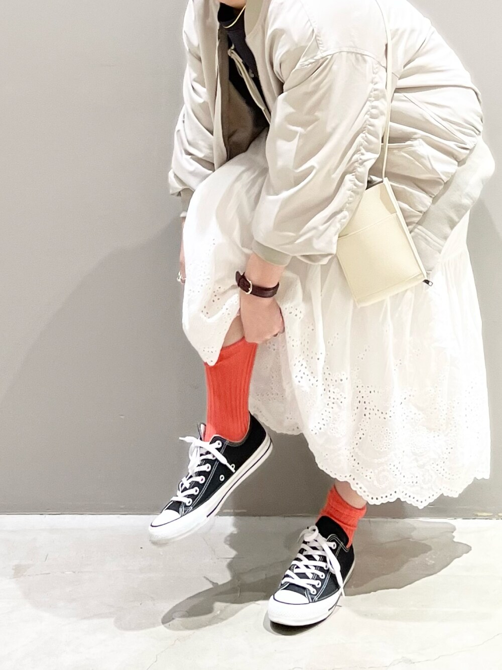ブラック系のスニーカー、ホワイト系のスカート、ホワイト系のショルダーバッグを着用したレディースの春コーディネートの1枚目の写真