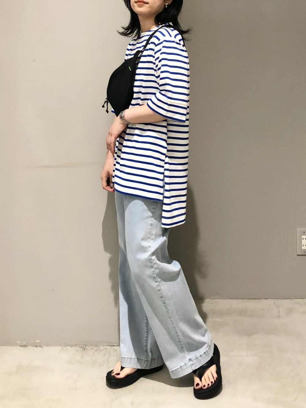 ブルー系のデニムパンツ、ブラック系のサンダル、ブルー系のTシャツ/カットソーを着用したレディースの夏コーディネートの2枚目の写真