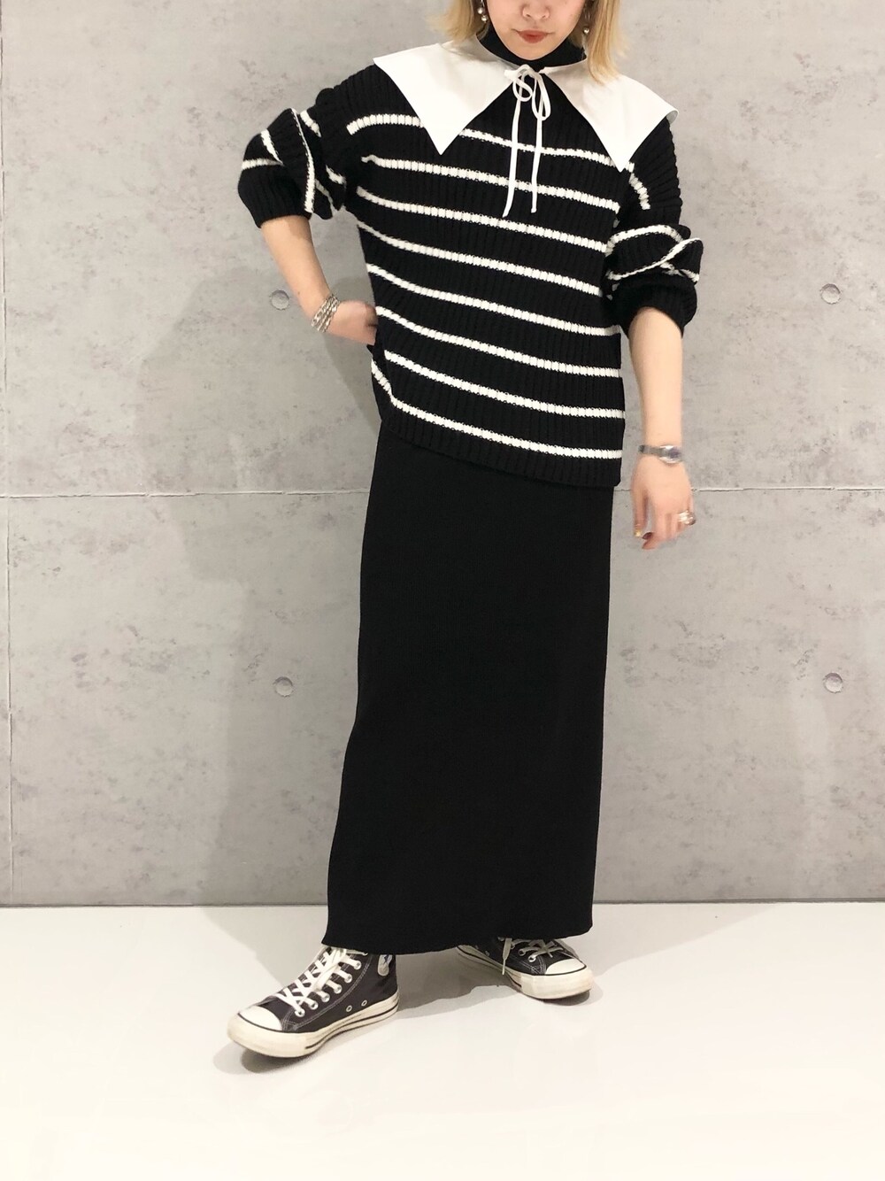 ブラック系のスカート、グレー系のスニーカー、ブラック系のニット/セーターを着用したレディースの冬コーディネートの2枚目の写真