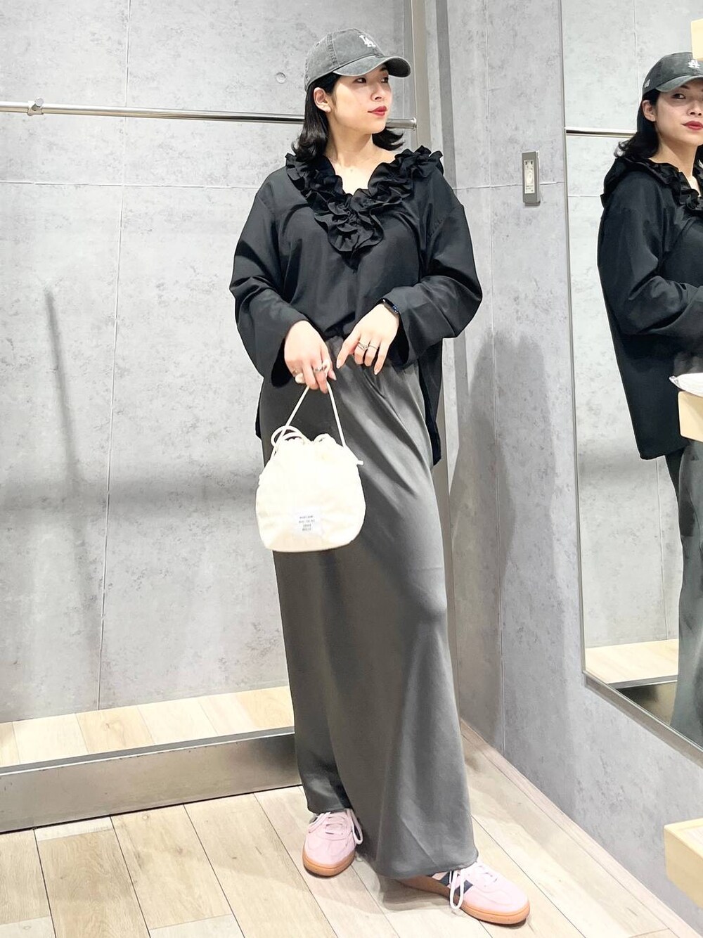 グレー系のスカート、ホワイト系のショルダーバッグ、ブラック系のキャップを着用したレディースの春コーディネートの1枚目の写真