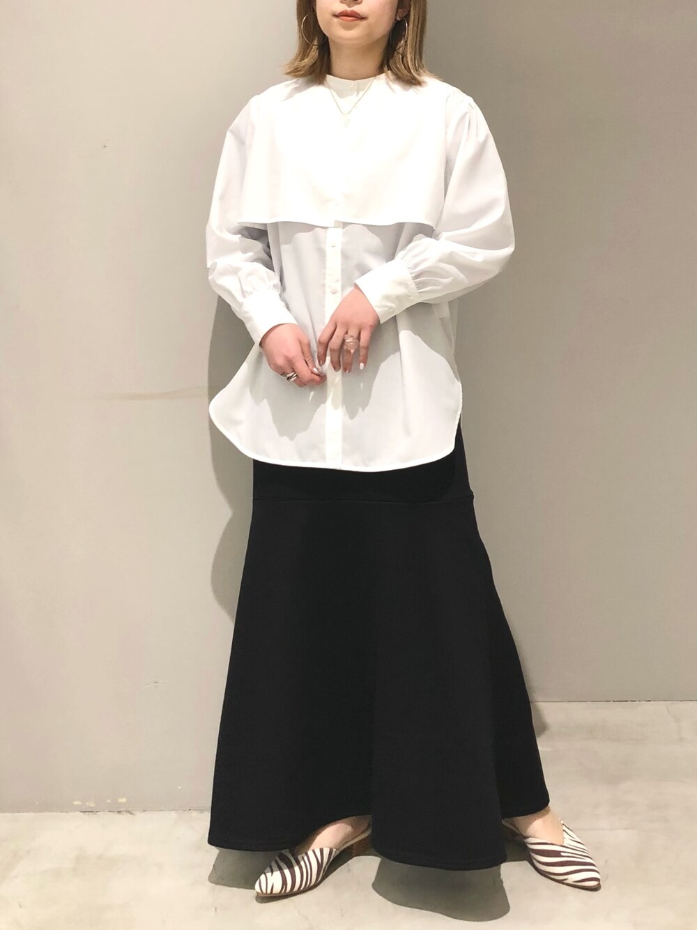 ホワイト系のシャツ/ブラウス、ブラック系のスカート、その他のサンダルを着用したレディースの春コーディネートの2枚目の写真